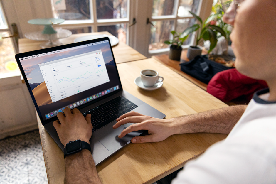 A person working on a laptop with business analytics displayed, showcasing a remote work setup in a cozy environment.